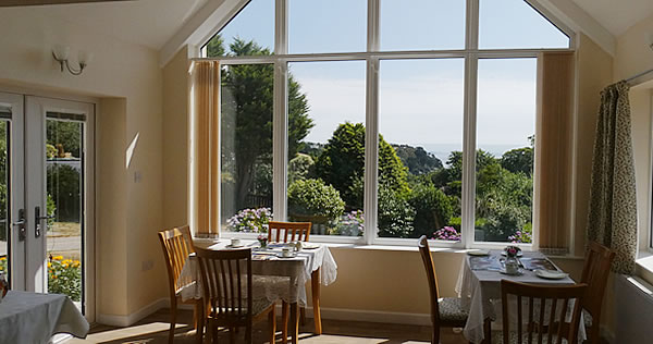 Relax over breakfast with views down a wooded valley to the sea